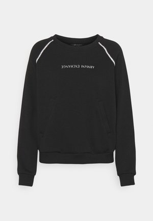 Černá mikina s kulatým výstřihem s stříbrnými proužky na ramenou a nápisem "ARMANI EXCHANGE" vytištěným vzhůru nohama na přední straně.