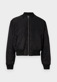 Chaqueta bomber negra, material sintético suave, diseño corto, cierre frontal con cremallera, puños y dobladillo acanalados, bolsillos laterales, detalles mínimos.