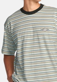 Randig kortärmad t-shirt i ljusblått, beige och svart. Har en rundad halsringning och en liten logotyp på vänster bröst. Mjuk bomullsmaterial.