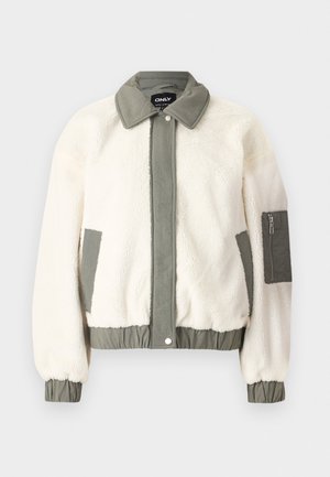 Cream-colored faux fur jacket with a green fabric waistband, collar, and cuffs. Features a zippered pocket on the left arm.