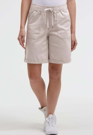 Beige knee-length shorts with rolled hems and front patch pockets, worn with white sneakers and a white top.