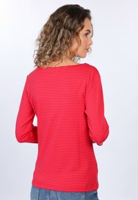 Langarmshirt in Rot mit horizontalen Streifen, aus einem weichen Material. Verfügt über einen weiten Halsausschnitt und einen lockeren Schnitt, kombiniert mit Jeans.
