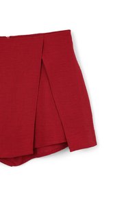 Gonna rossa, strutturata, con design avvolgente e dettagli di piega laterale. Presenta una chiusura con zip nascosta sul retro. Lunghezza corta.