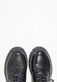 Bottes en cuir noir avec un motif texturé de crocodile, bouts ronds et semelles en caoutchouc robustes. Elles présentent des lacets noirs et un design minimaliste.