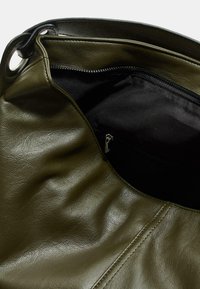 Borsa a tracolla in pelle verde oliva con una superficie liscia, dotata di una tasca interna con cerniera e un'apertura curva, che mostra un interno nero.