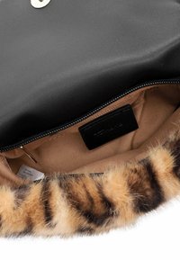 Schwarze Lederinnentasche mit beigem Stofffutter, ausgestattet mit einem glatten Reißverschluss und einem Kunstfellbesatz mit braunen und beigen Streifen. Ein schwarzes Etikett ist sichtbar.
