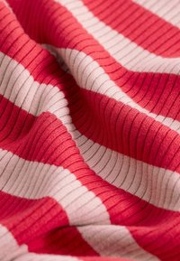 Tessuto a righe caratterizzato dai colori rosso e beige chiaro, con una texture a coste che alterna strisce larghe, creando una superficie morbida e tattile.