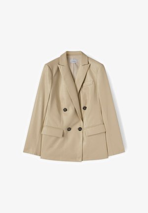 Beige dobbeltbrystet dameblazer med hakknaphakke, to forlommer med klap og mørke, runde knapper, lagt fladt.