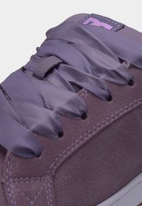 Μωβ σουέντ αθλητικό παπούτσι με φαρδιές σατέν λιλά κορδόνια δεμένα σε φιόγκο, λεπτομερής ραφή, και λευκή καουτσούκ σόλα ορατή στο κάτω άκρο.