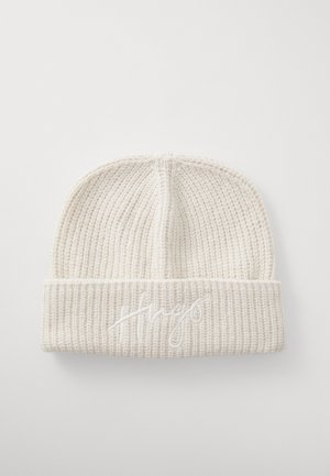 Cream-colored ribbed knit beanie with folded cuff embroidered with the word "Hugo" in matching thread.