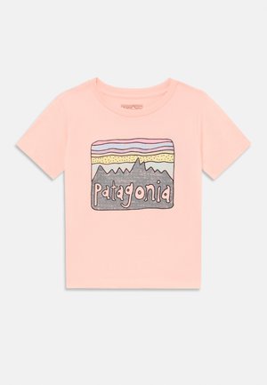 T-shirt de algodão rosa com um design gráfico de montanhas e a palavra "Patagonia" em fonte divertida. Mangas curtas, corte clássico.