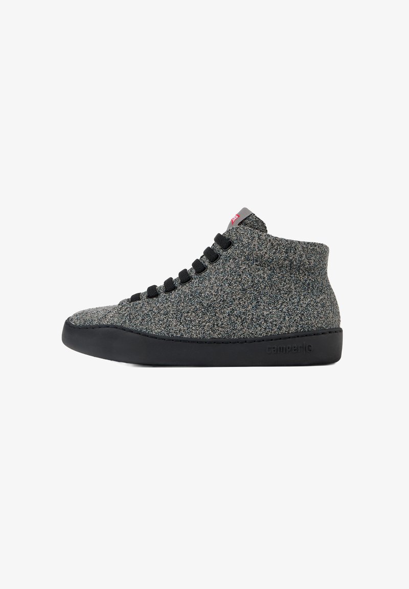 Harmaa teksturoitu korkea sneaker mustalla kumipohjalla, jossa on mustat nauhat ja punainen brändilogo kielen päällä.