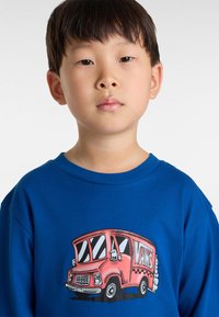 Blauwe lange mouwen t-shirt met een grote graphic van een rode food truck met "VANS" op de zijkant, zwarte accenten en witte wielen.