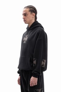 Black hooded sweatshirt with a front pocket, featuring metallic printed accents on the chest and sleeves, in a relaxed fit. Soft texture.