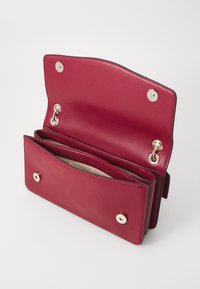 Portafoglio in pelle rossa con una superficie liscia, dotato di chiusura a doppio scatto, numerosi scomparti interni e dettagli in metallo dorato.