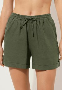 Grønne lin shorts med elastisk talje, snor og op-rullede manchetter. Letvægtigt stof med en tekstureret overflade.