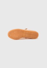 Adidași roz cu o talpă din cauciuc texturat, având un model geometric și un accent circular. Superior din material moale, cu închidere ajustabilă.
