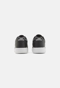 Svarta lädersneakers med en vit gummisula, rund tå och "new balance"-logotyp på hälen. Klassisk atletisk design.