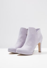 Lilac suede nilkkurit korkealla korolla, joissa on pyöristetty kärki ja vetoketju sivussa. Sileä pinta ja minimalistinen muotoilu.