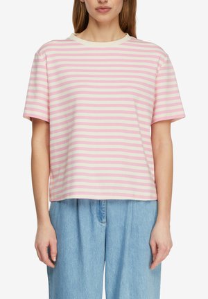 Donna che indossa una t-shirt a maniche corte con righe orizzontali rosa e panna e jeans a vita alta azzurri chiaro su sfondo bianco.