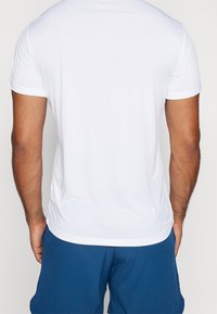 Valkoinen lyhythihainen urheilupaita, jossa on teksturoitu kangas, pyöreä kaula-aukko ja kontrastiväriset saumat. Sopii urheiluun tai vapaa-aikaan.