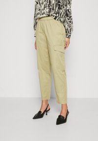 Beige cargo kalhoty s volným střihem, se bočními kapsami a elastickým pasem. Spárované s černými slingback podpatky.