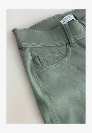 Kõrge vöökohaga rohelised retuusid, sileda tekstuuriga, väikese eesmise tasku ja kontrastse õmblusega.