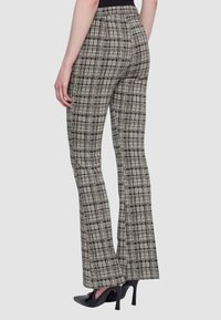 Pantaloni a zampa d'elefante a quadri in tessuto bianco e nero, con vita alta e vestibilità sagomata. Texture liscia con motivo a quadri.