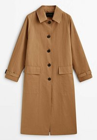 Long trench beige avec col pointu, cinq boutons noirs sur le devant, deux poches à rabat et des sangles de manchette ajustables.