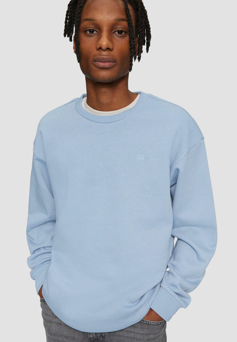 Lichtblauwe sweatshirt van zacht materiaal, met een ronde hals en mouwboorden. Klein logo op de borst, relaxte pasvorm.