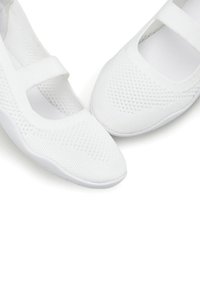 Weiße Mesh-Schuhe mit flacher Sohle und einem Riemen über dem Spann, mit einer strukturierten Oberseite und einer glatten, runden Zehenpartie.