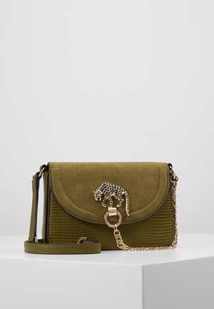 Zielona torebka na ramię o teksturowanej powierzchni, zamszową klapką, złotym łańcuszkiem i złotym ozdobnym zapięciem w kształcie lamparta, na białym tle.