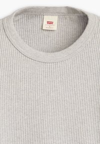 Gray, ribbed long-sleeve top with a crew neckline. Label at the collar reads "Levi's Relaxed Fit." Soft fabric texture.