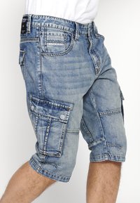 Svijetloplave traper cargo kratke hlače s više džepova, s preklopljenim rubom i šivanim detaljima, s oznakom "KRS Denim Od 2001."