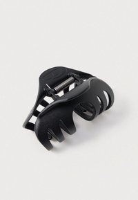 Fekete műanyag hajcsat, ívelt kialakítással, több rögzítőfoggal, rugós mechanizmussal és nyitott kivágásokkal a rugalmasság érdekében.