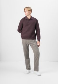 Knitted plum sweater with a polo collar and textured pattern, paired with light gray corduroy pants and white sneakers.