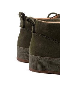 Bottines en daim vert olive avec des semelles en caoutchouc texturé, des détails de couture et des languettes pour un enfilage facile.