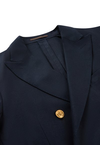 Marineblauer Blazer mit breiten Revers und einer einzelnen dekorativen goldenen Knopf mit erhabenem Emblem.