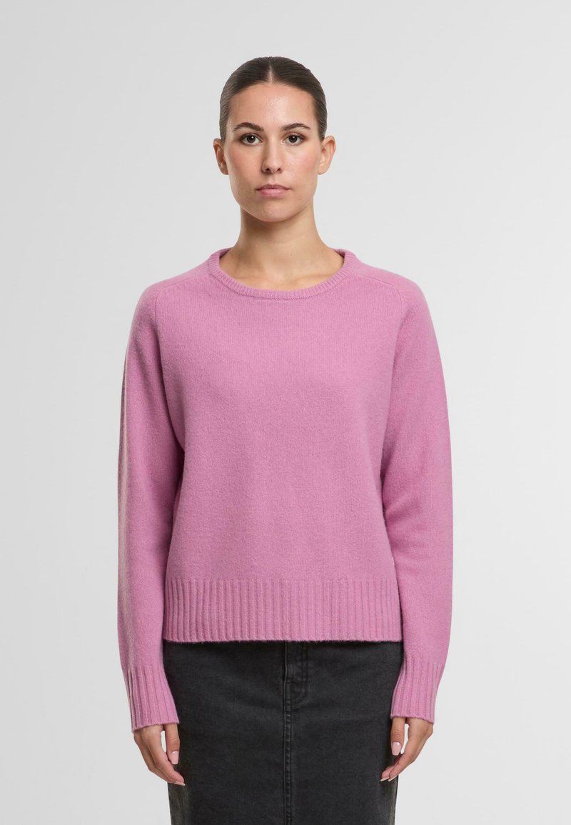 Rosa gestrickter Pullover mit rundem Halsausschnitt, gerippten Bündchen und Saum. Weiche Textur, lockere Passform und abgefallene Schulternähte. Einfaches Design.