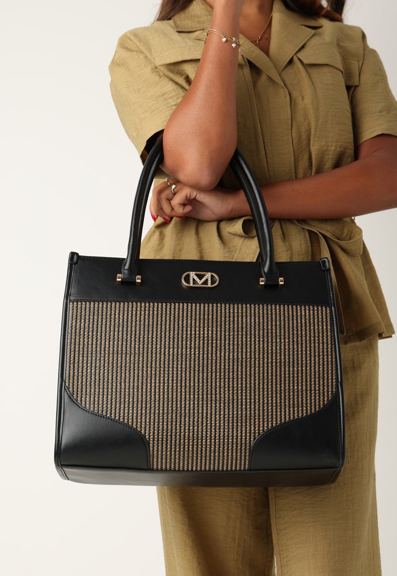Svart strukturerad handväska med vävt beigt mönster, släta läderdetaljer och guldhårdvarulogga. Dubbla handtag för bärande.