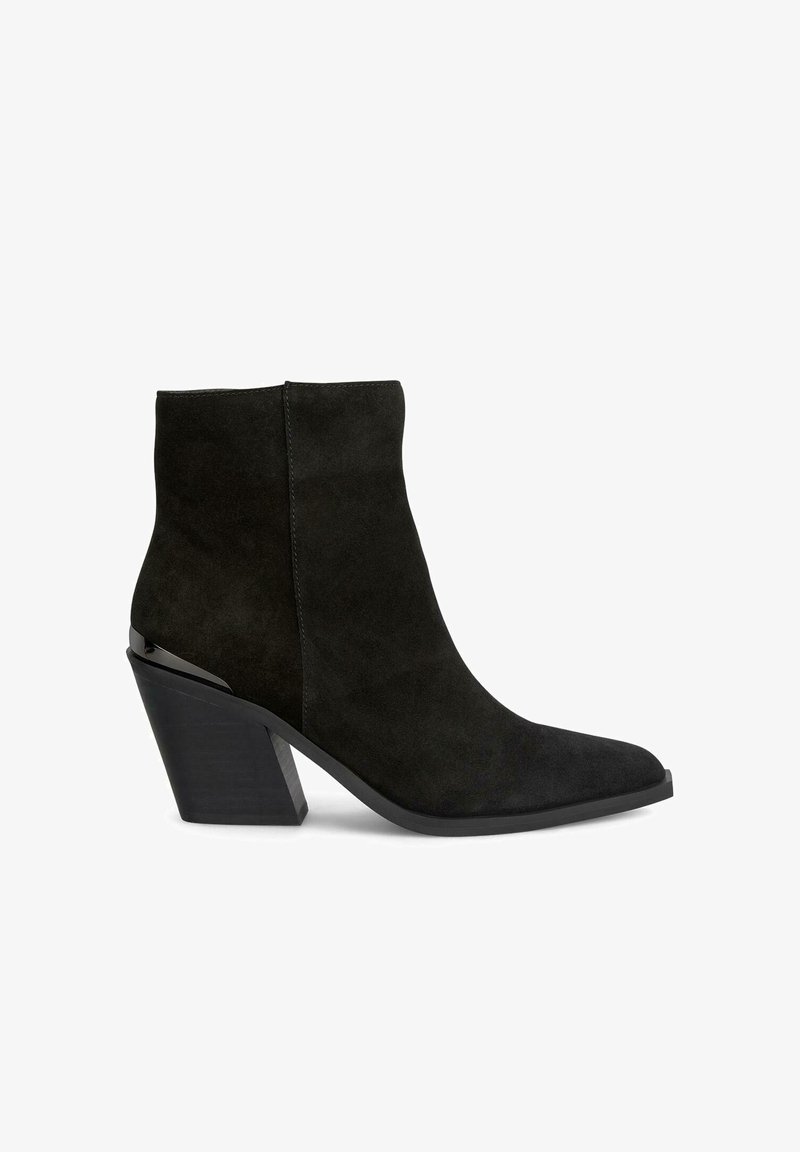 Bottine en suede noir avec un bout pointu, présentant un talon géométrique imposant et un design épuré et minimaliste.