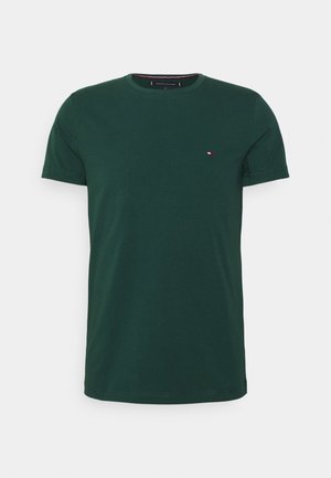 Dunkelgrünes T-Shirt mit kurzen Ärmeln und Rundhalsausschnitt mit kleinem rechteckigem rot-weiß-blauem Logo auf der linken Brust.