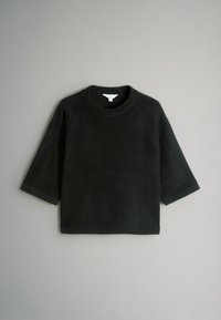 Musta fleece-paita ympyräkauluksella, kolmanneksen pitkillä hihoilla ja rentolla istuvuudella. Pehmeä pinta ilman kuvioita tai metalliyksityiskohtia.