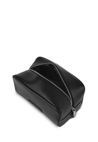 Czarna skórzana kosmetyczka o teksturowanej powierzchni, z dwoma ukośnymi zamkami błyskawicznymi i prostokątnym kształtem.