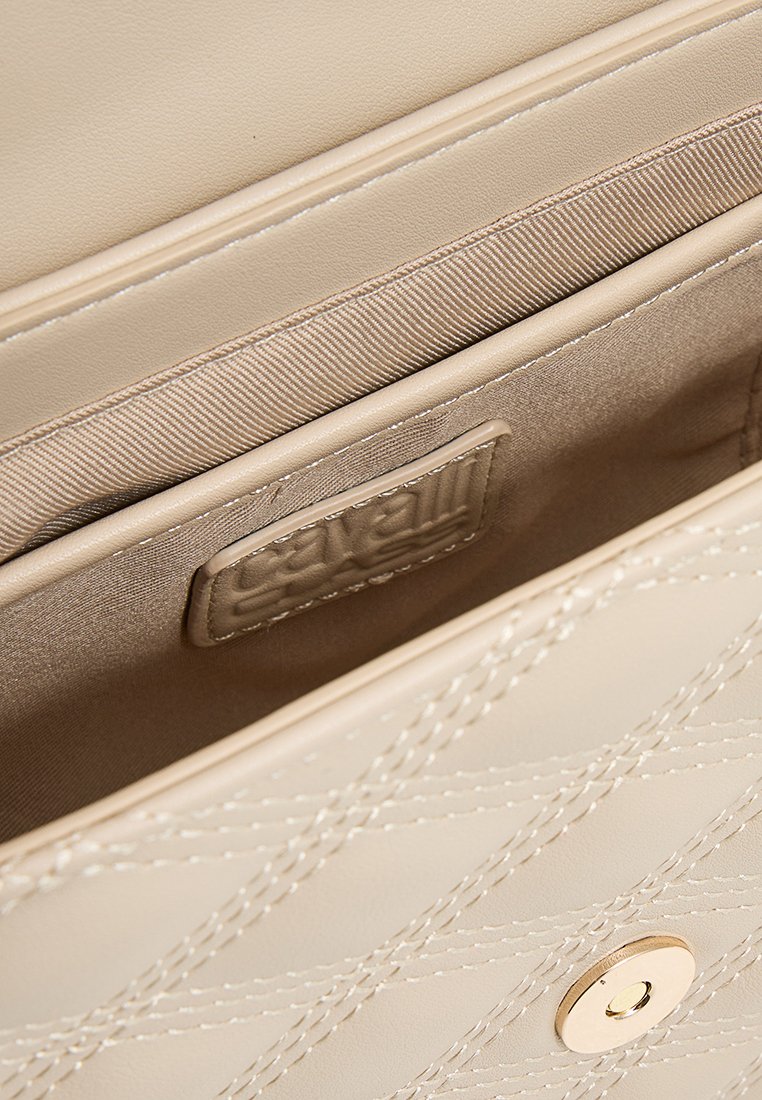 Interno della borsa a mano in pelle beige con motivo trapuntato, texture liscia, chiusura magnetica singola e foderatura in tessuto interno.