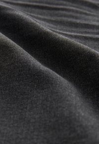 Nahaufnahme eines weichen, dunkelgrauen Stoffes mit feiner Textur und sanften Falten, die die Materialqualität und Oberflächendetails hervorheben.