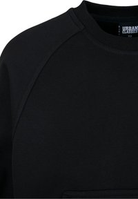 Sweat-shirt noir à col rond avec manches raglan et étiquette "Urban Classics" à l'intérieur du col, taille XS.