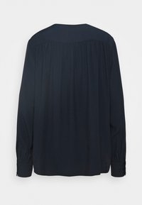 Blusa a maniche lunghe blu scuro con una sottile texture a puntini, dettaglio plissettato sullo schienale e polsini con bottoni.