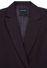 Blazer su misura di colore viola scuro con revers, tasca sul petto, e etichetta nera con la scritta "CALLIOPE S" sulla fodera in satin.