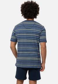 Gestreiftes T-Shirt in Blau-, Grün- und Cremetönen. Kurze Ärmel, runder Halsausschnitt, lockerer Schnitt. Kombiniert mit dunkelblauen Shorts.
